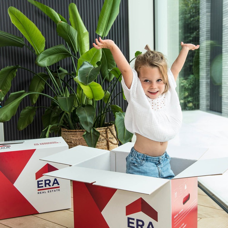 Een meisje springt uit een ERA verhuisdoos.