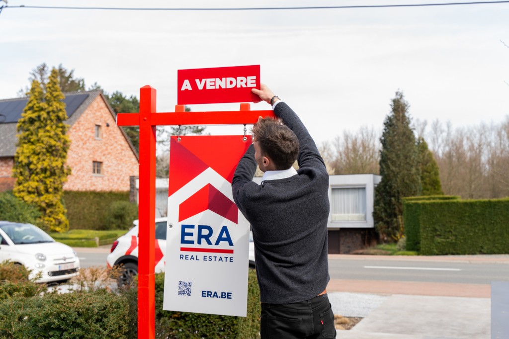 L'agent immobilier place à vendre sur le poteau de jardin