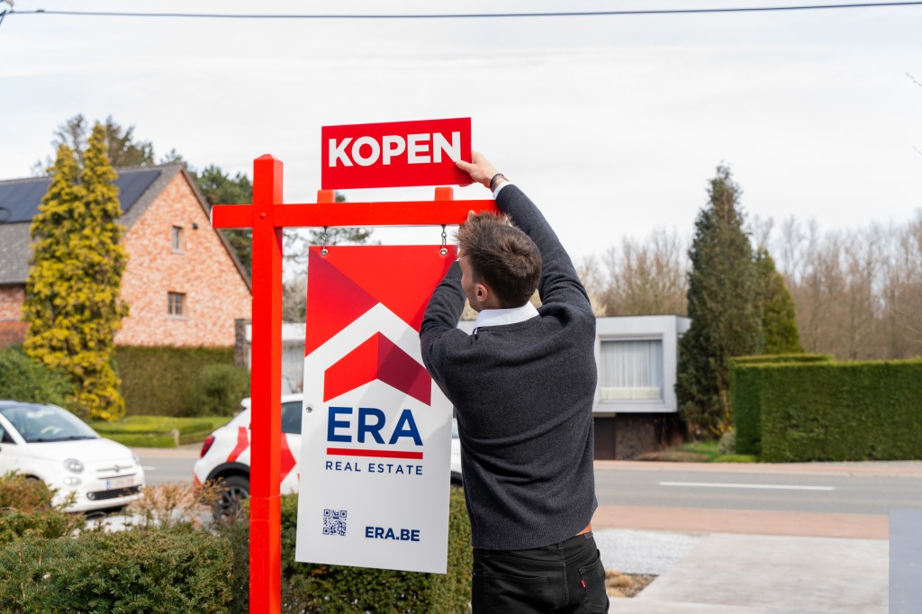 Makelaar plaatst kopen op tuinpaal